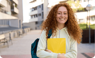 Frame 1618873935 Student with backpack and notebook, smiling outdoors.